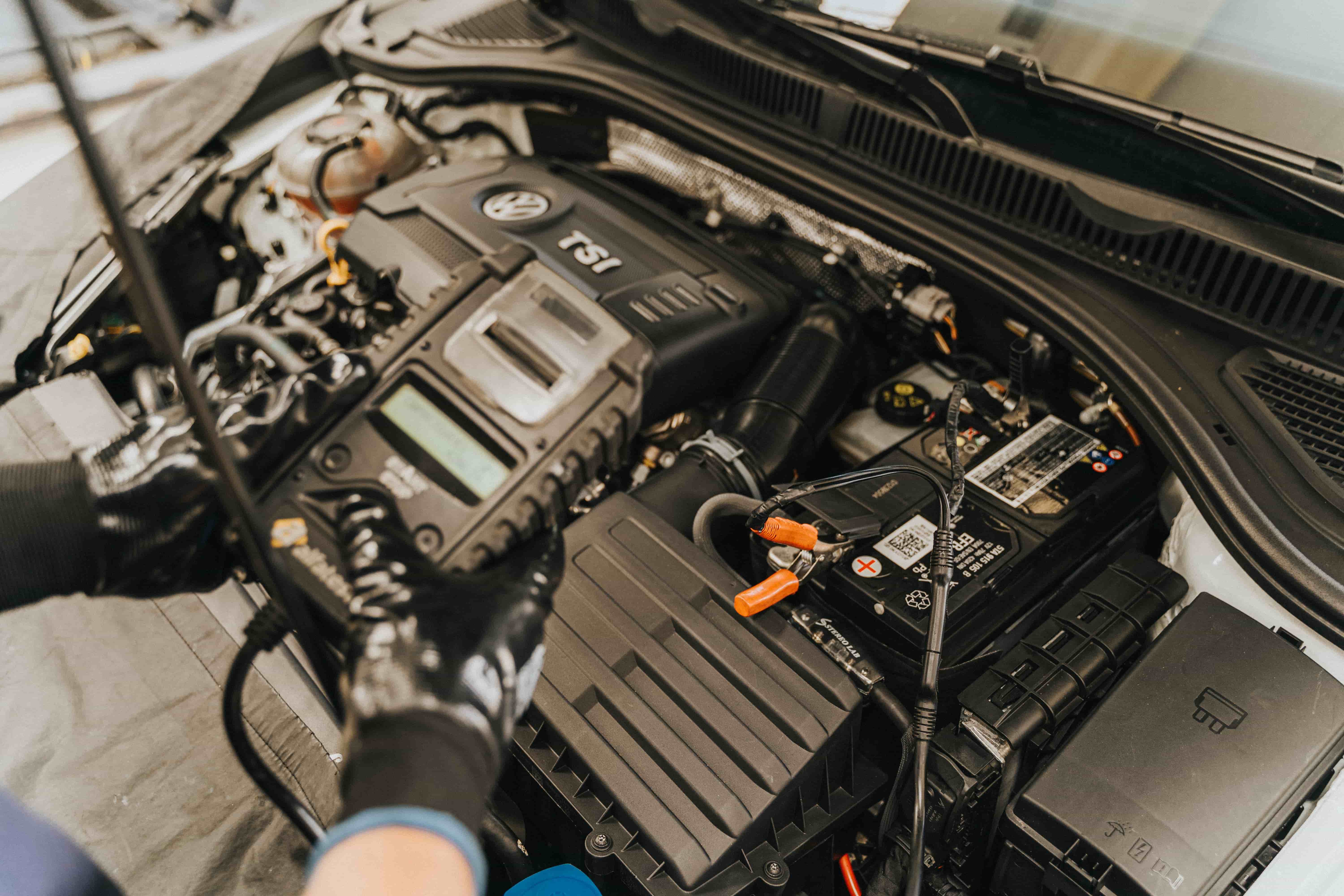 Mechanic testing a car battery during a no-start diagnosis in a Clarksville driveway